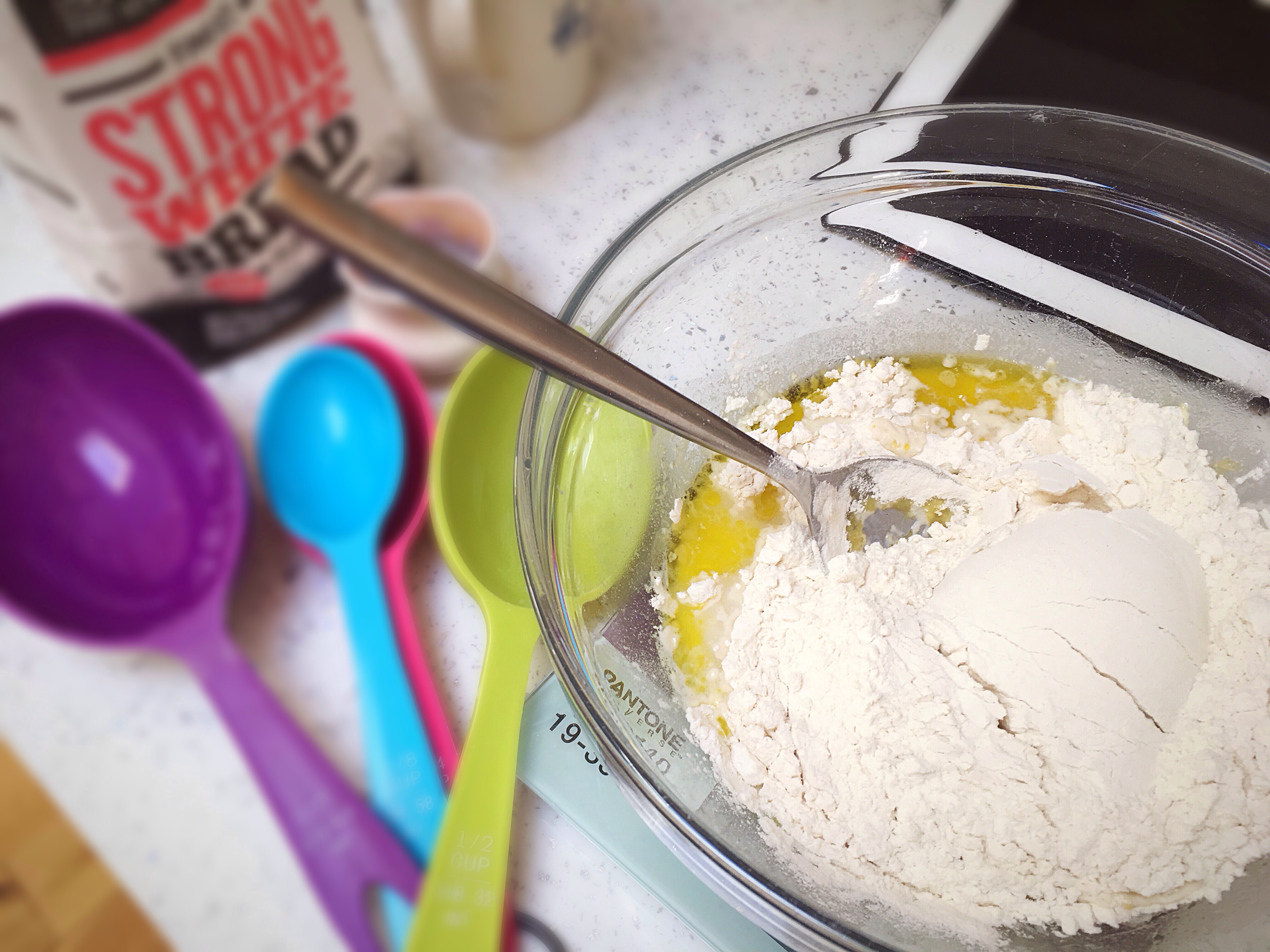 A bowl of flour and spoons on the table.