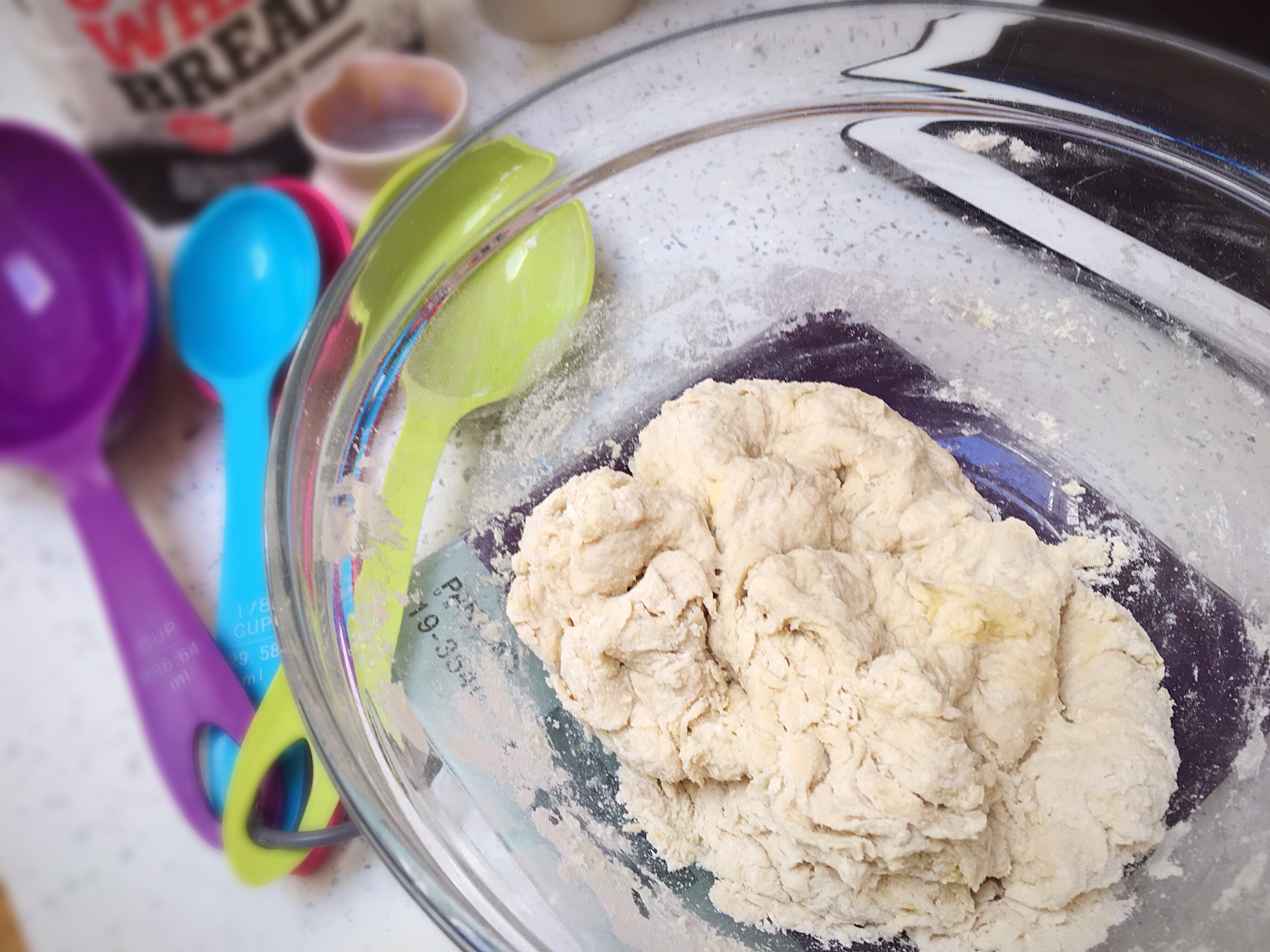 A bowl of dough is sitting on the table.