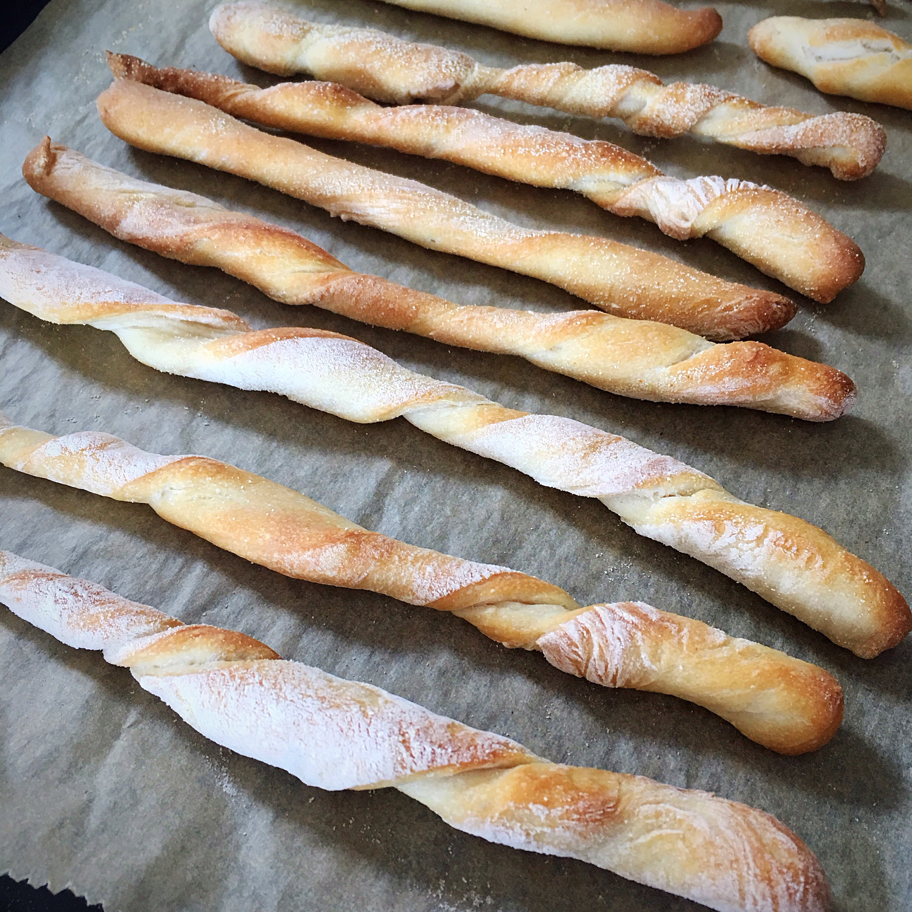 A bunch of bread sticks sitting on top of a sheet.