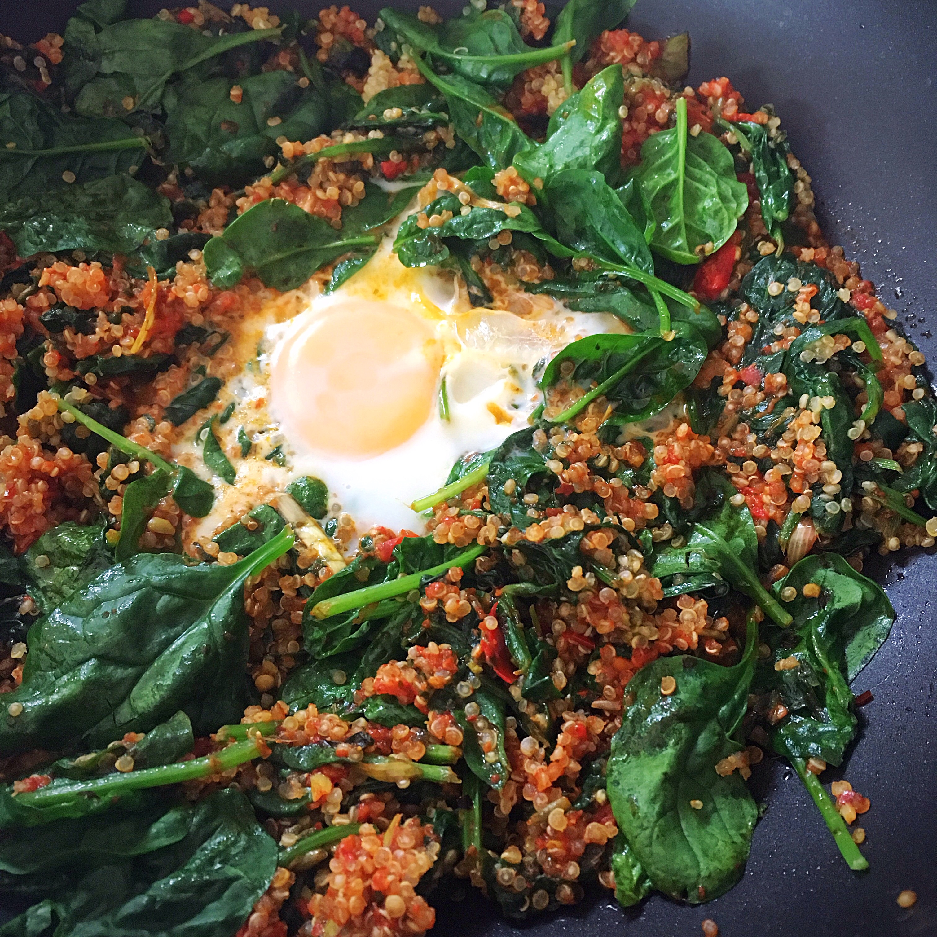A bowl of food with spinach and an egg on top.