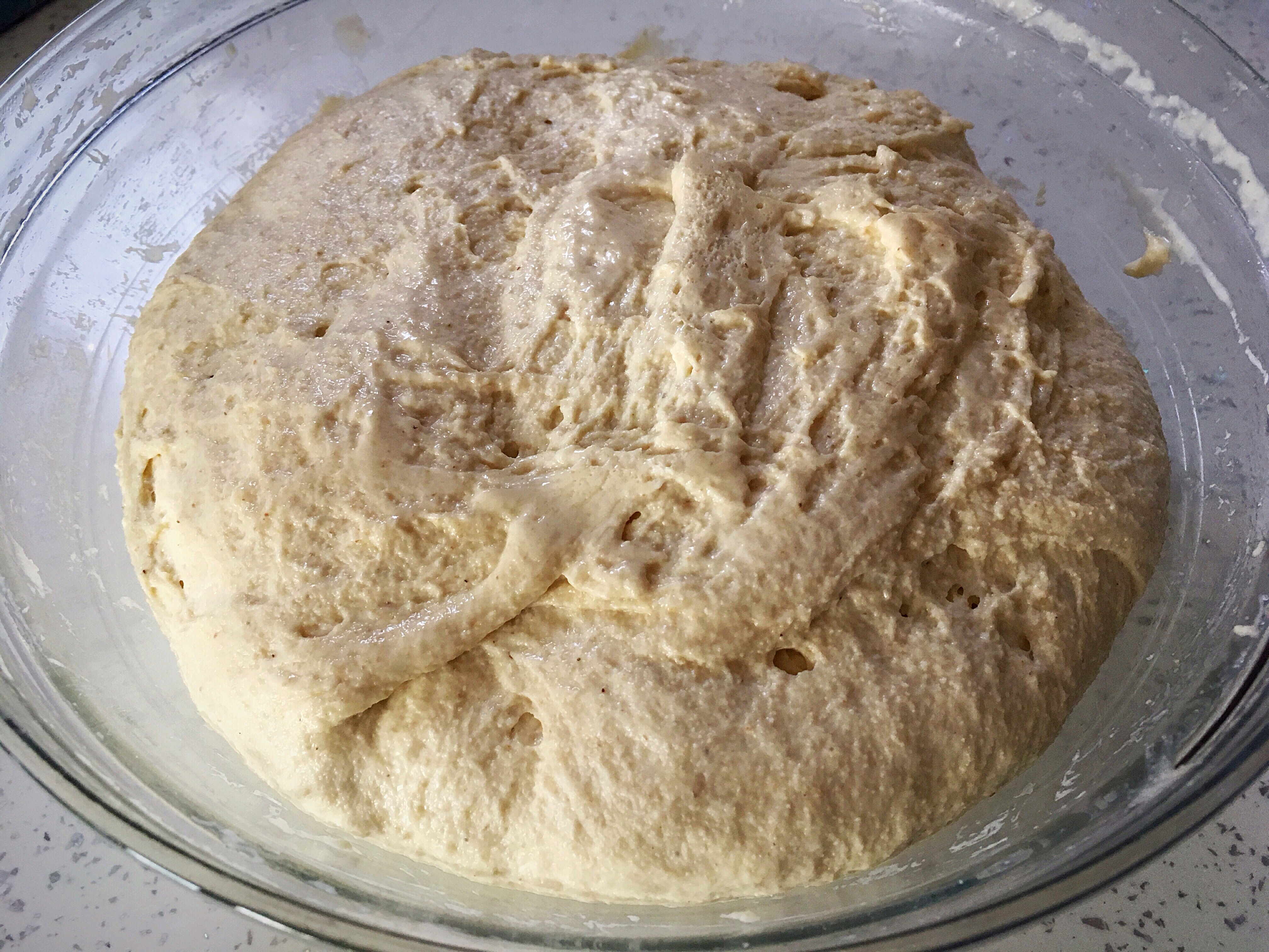 A bowl of dough is sitting on the counter.