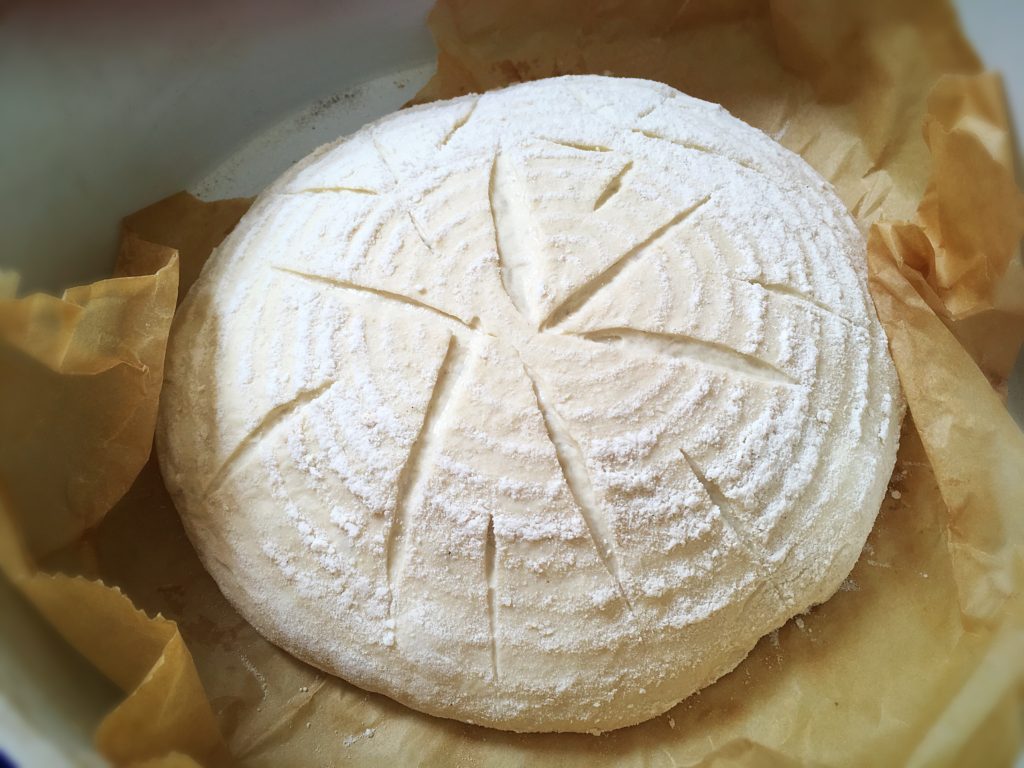 A round white cheese sitting on top of some brown paper.