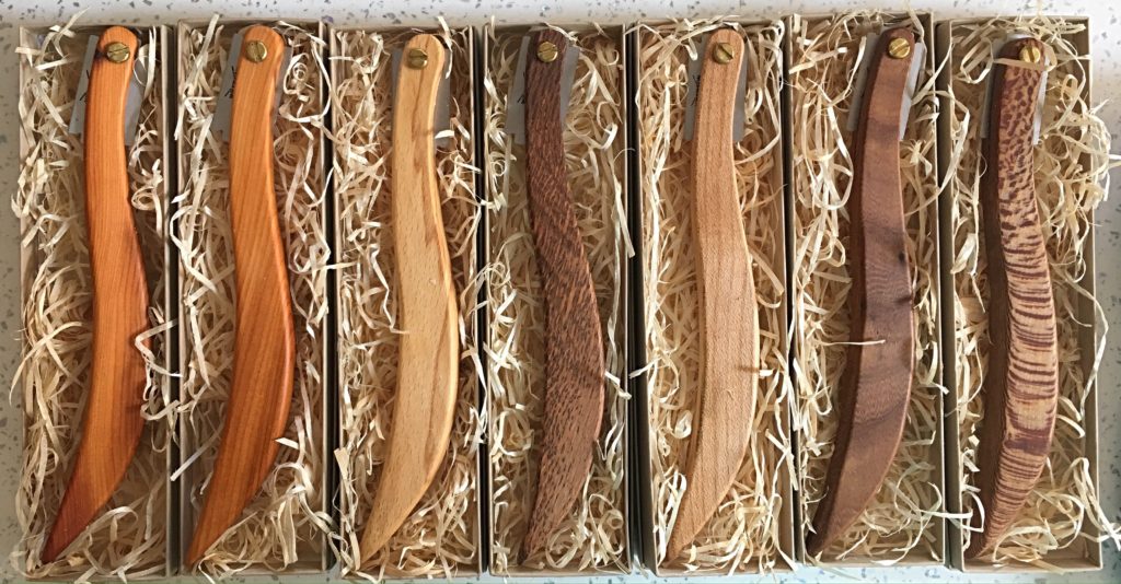 A group of wooden knives in a box.