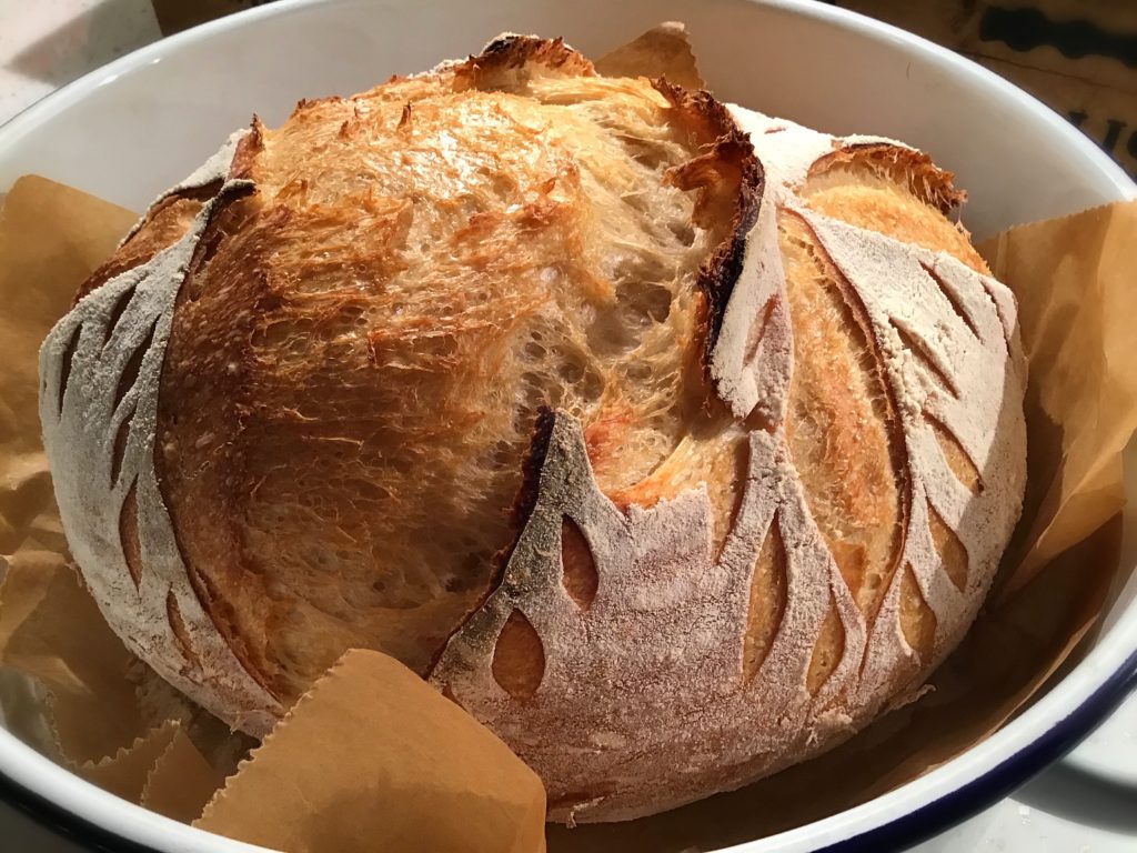 A loaf of bread in a bowl with some butter.