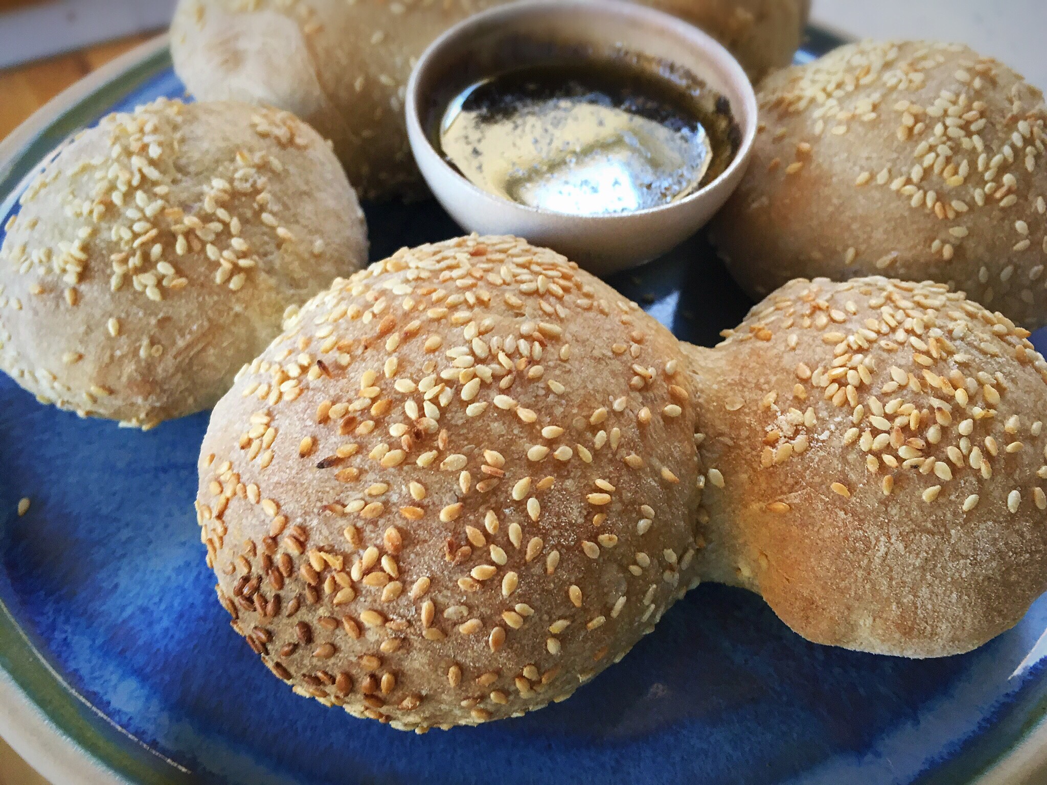 A plate of sesame seed rolls with dipping sauce.