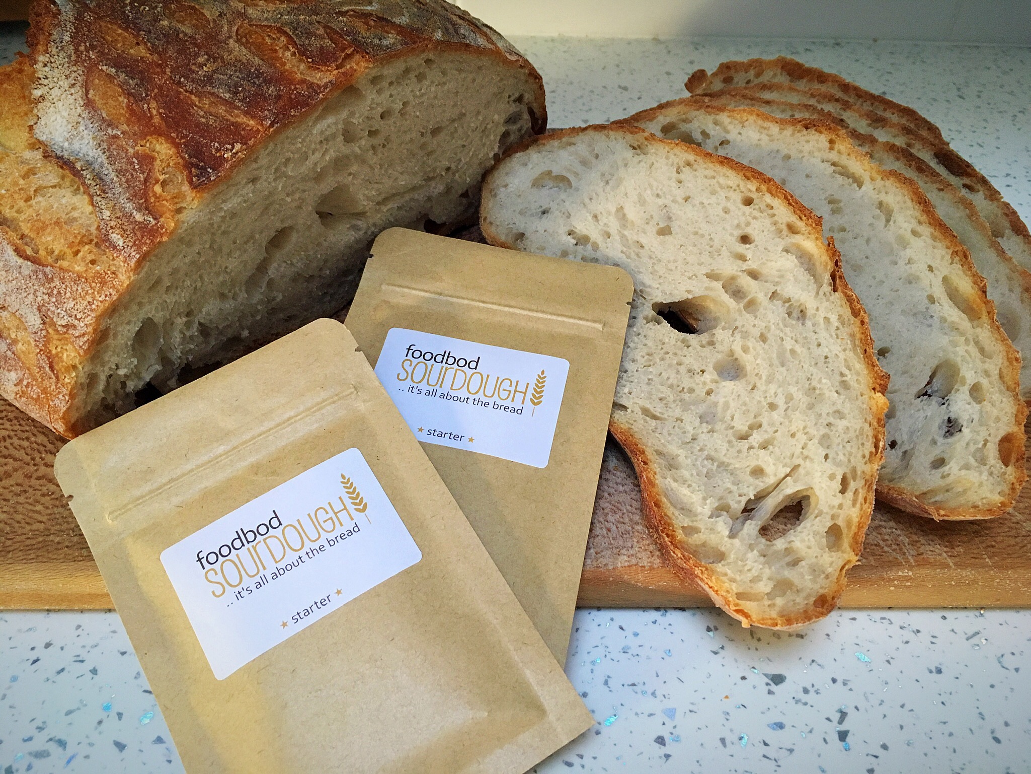 A loaf of bread next to two bags of flour.