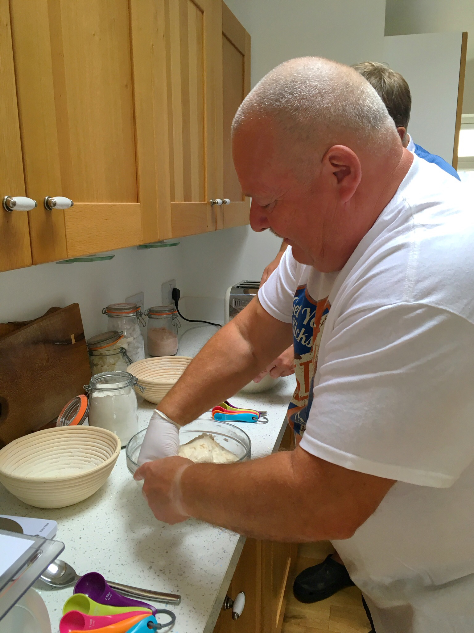 A man in white shirt preparing food on top of counter.