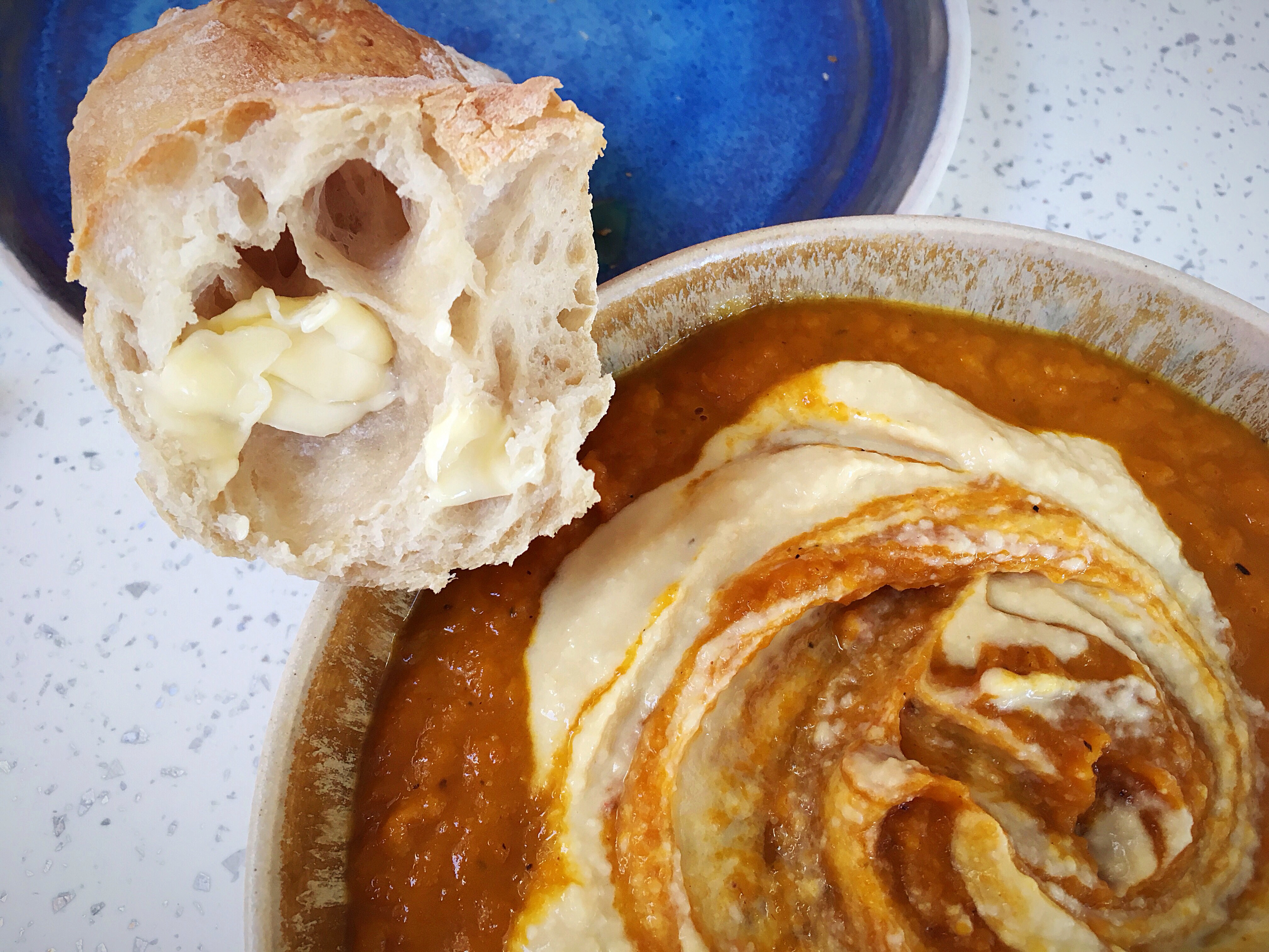 A bowl of hummus and bread on the table.