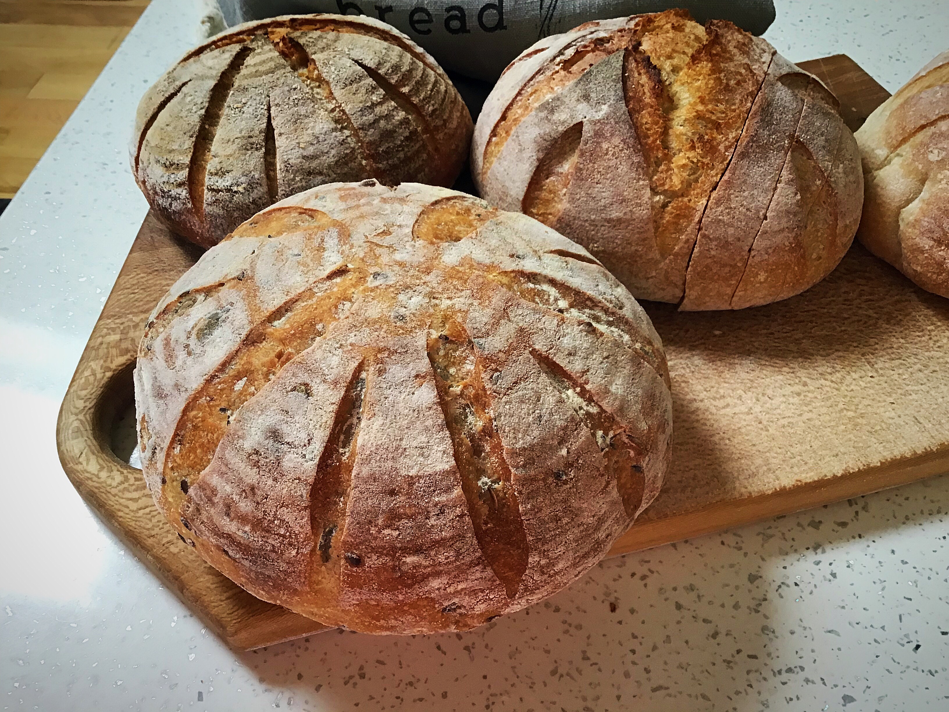 Three loaves of bread on a cutting board.