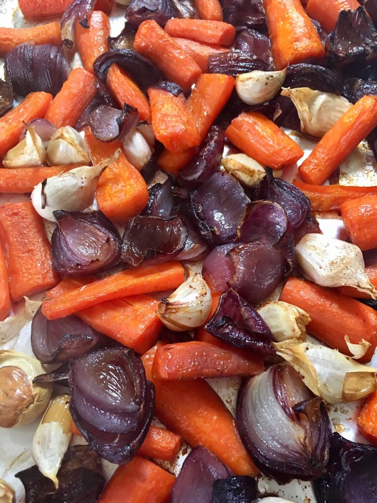 A close up of carrots and onions on the pan