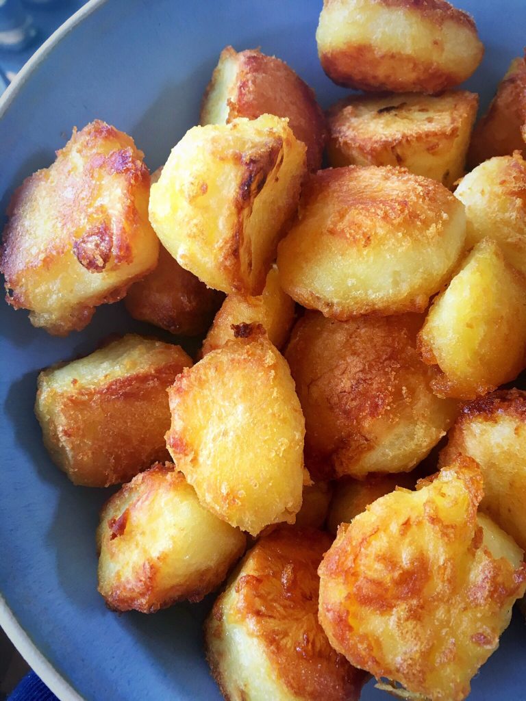 A blue bowl filled with potatoes covered in cheese.