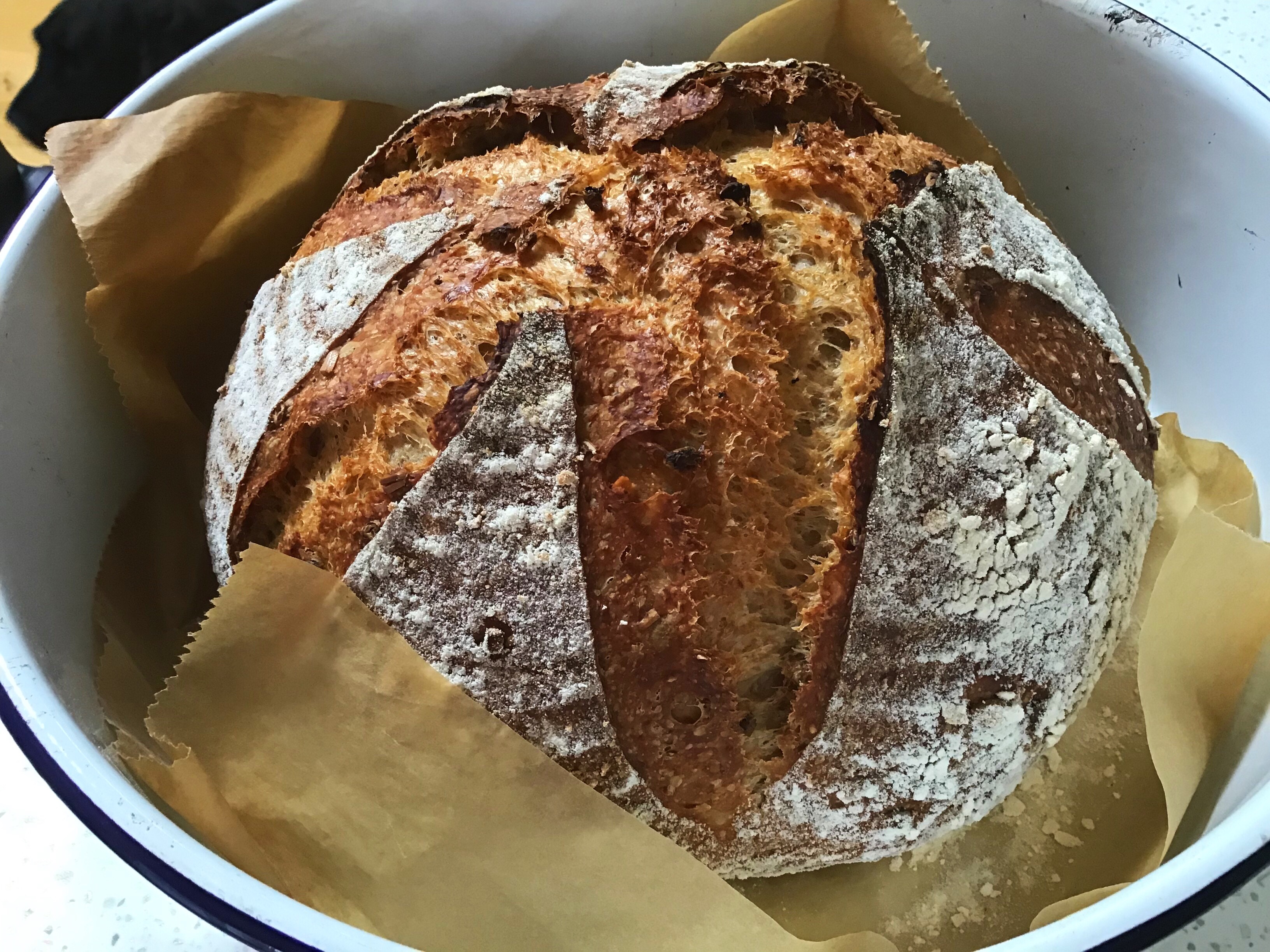 A loaf of bread in a bowl on wax paper.