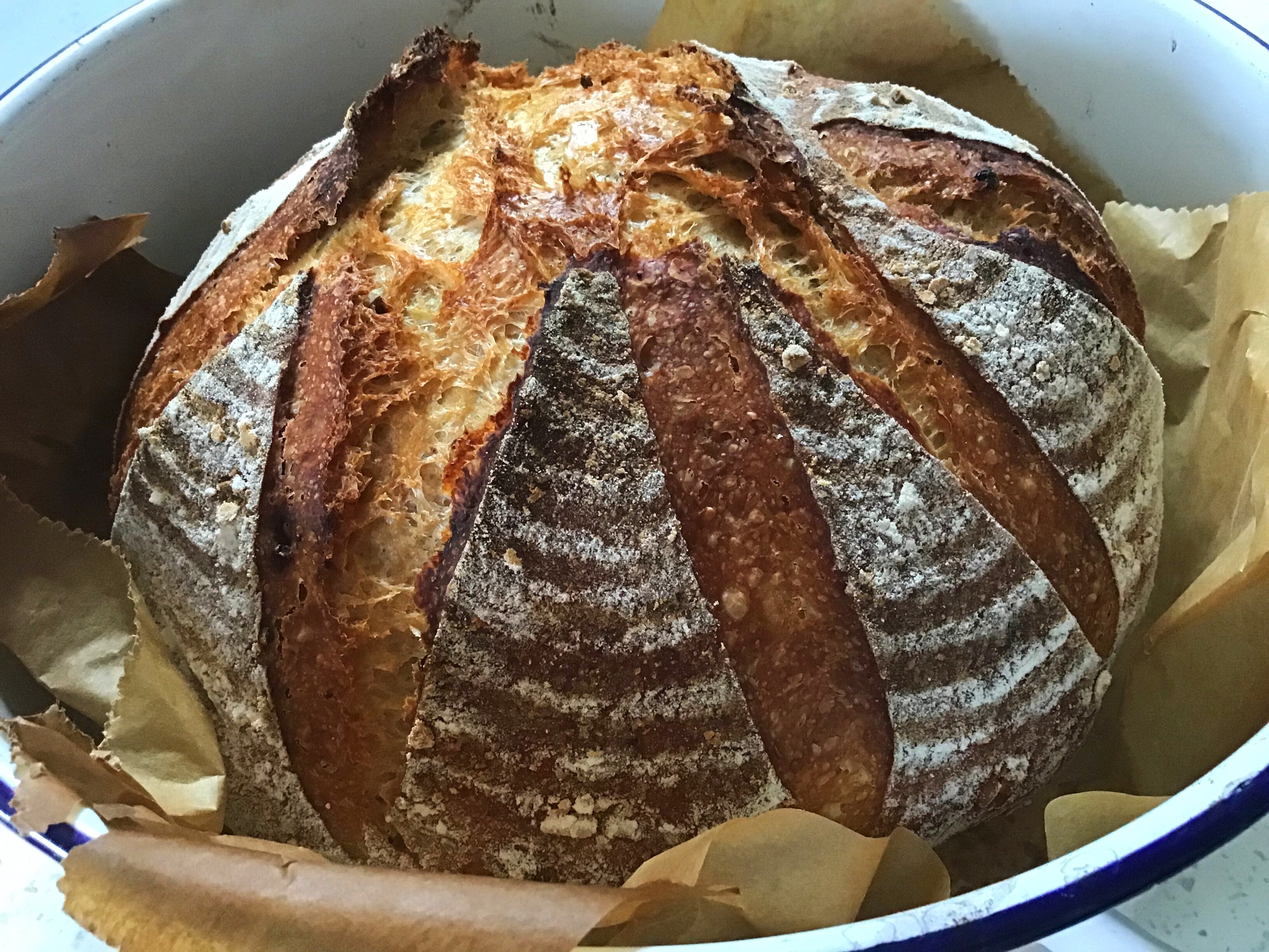 A loaf of bread in a bowl with some potato chips.