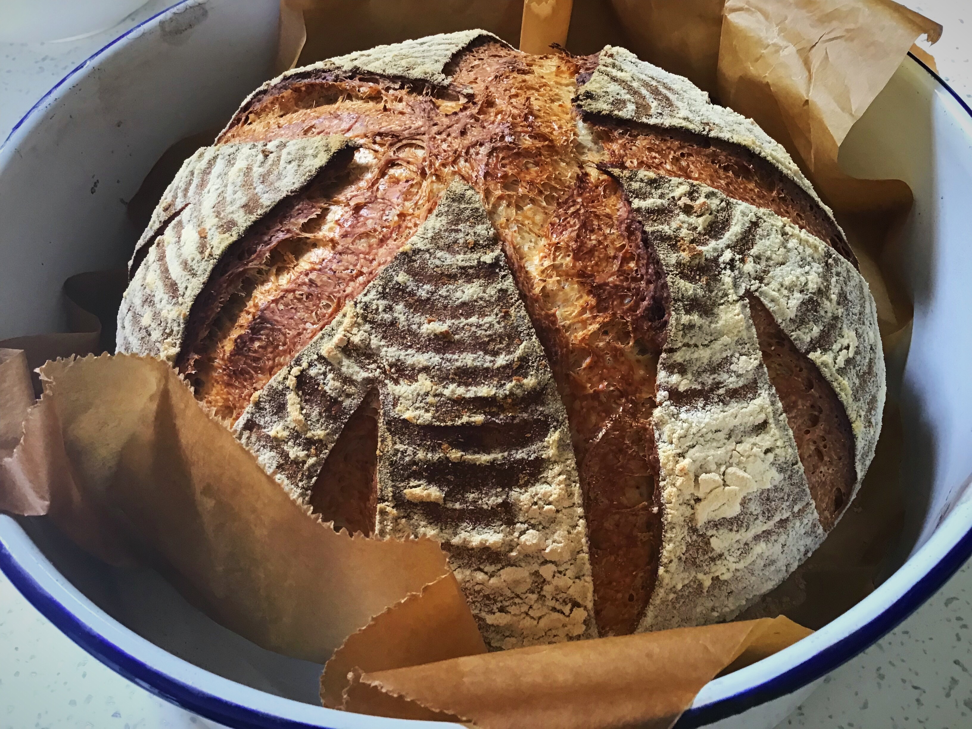 A loaf of bread in a bowl with some brown paper.