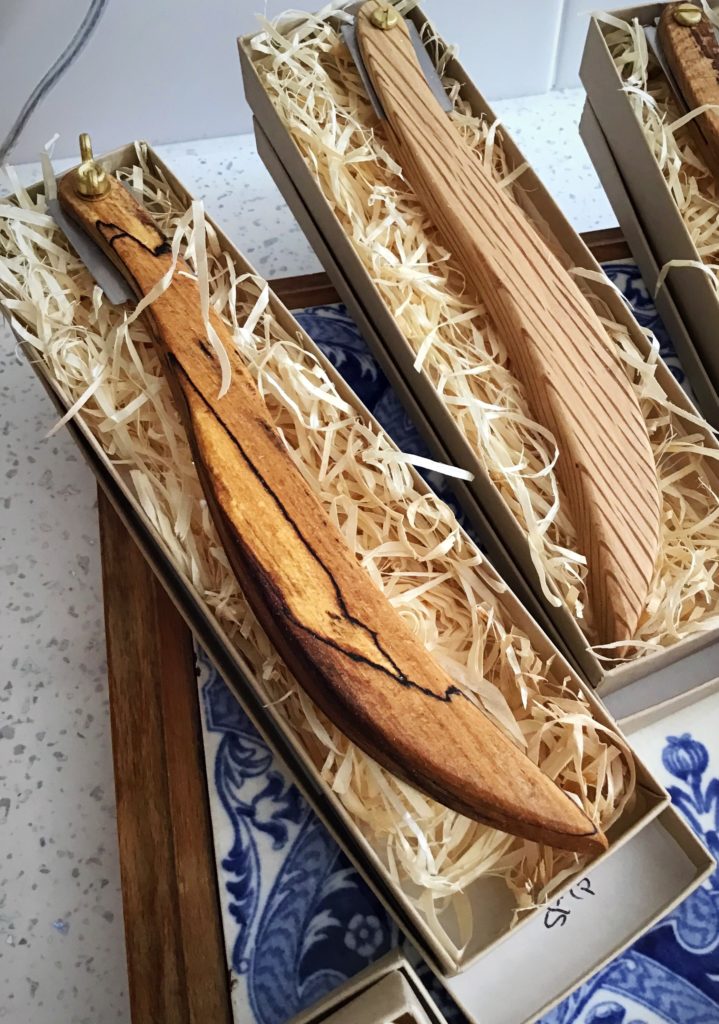 A wooden knife in a box with some wood shavings