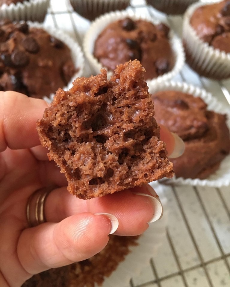 A person holding a bite of chocolate muffin.