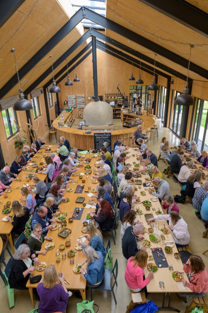 A large group of people sitting at tables eating.