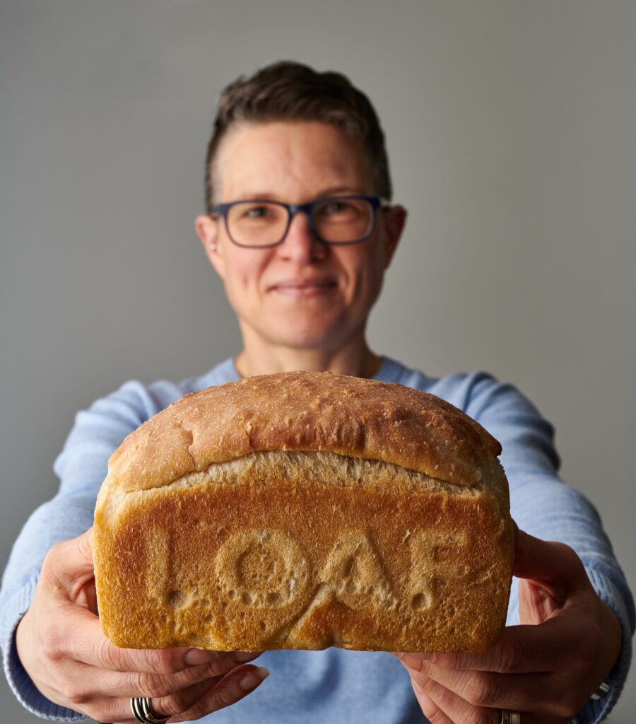 A woman holding up a loaf of bread.